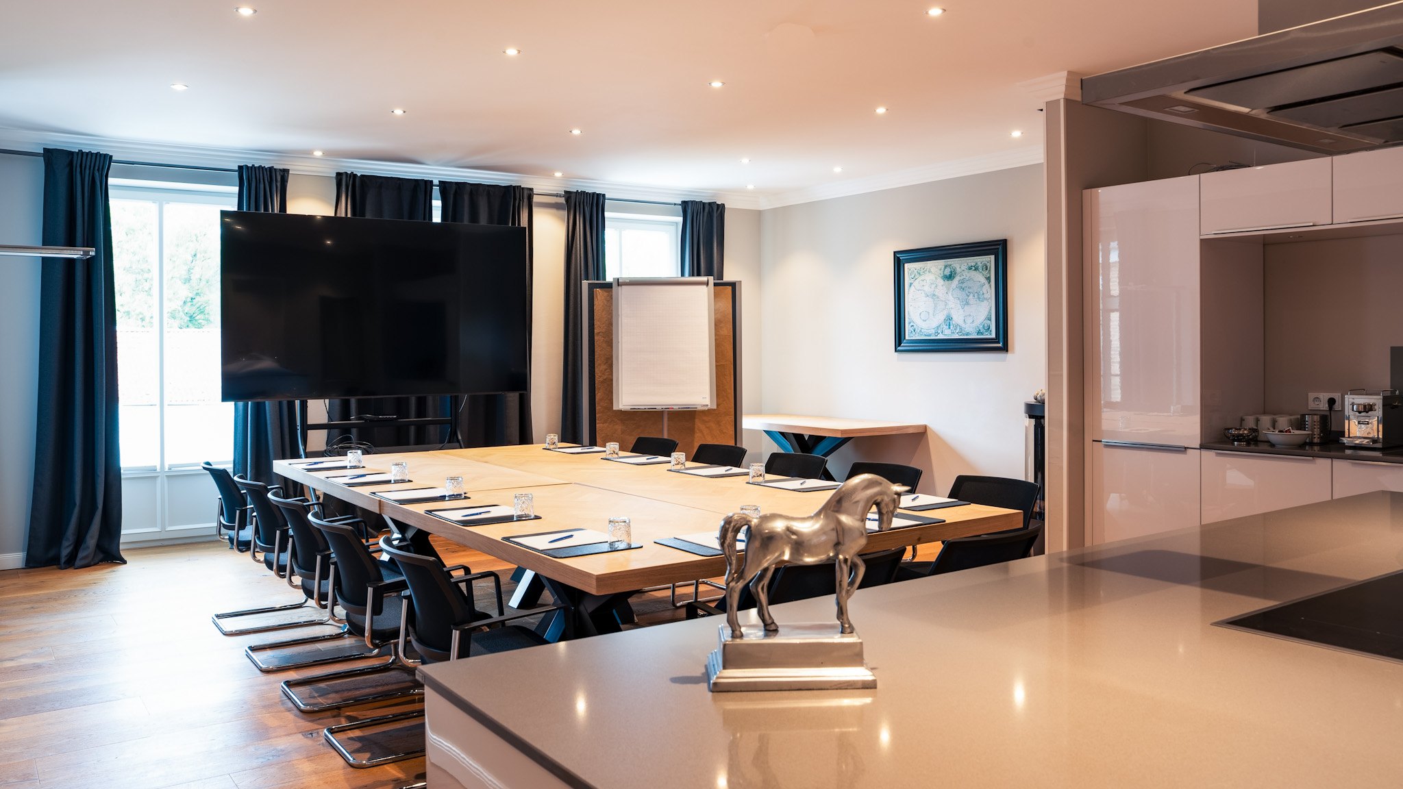 Tagungsraum Clubzimmer auf Gut Altona mit Konferenztisch, großem Bildschirm, Flipchart und eigener Küchenzeile